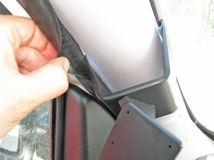 En hand håller i en del av bilens inredning, troligen från Fiat Doblo.