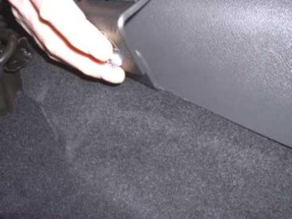 En hand som greppar en monteringsbygel på en bilinteriör.