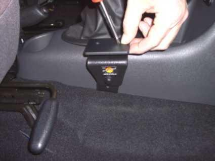 En hand håller i en skruvmejsel som fäster en konsol i en bil.