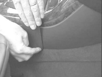 Hand som justerar eller installerar en konsol i en BMW X5.