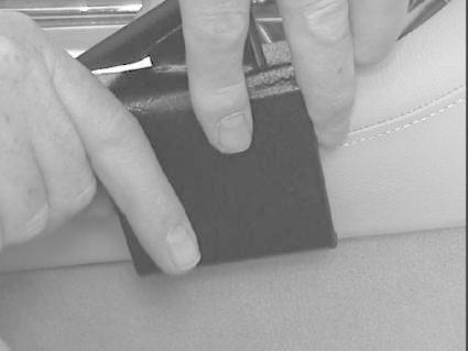 En person fäster en svart monteringsbygel på en bilkonsol.