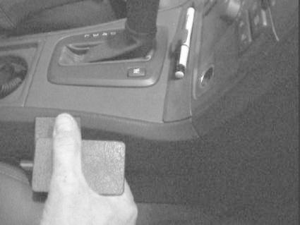 En hand håller i en konsoldel från en Volvo V70, med växelspak och knappar.