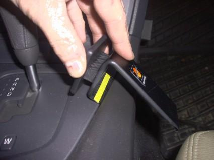 En hand håller i en konsoldel för Volvo S60 00-04.