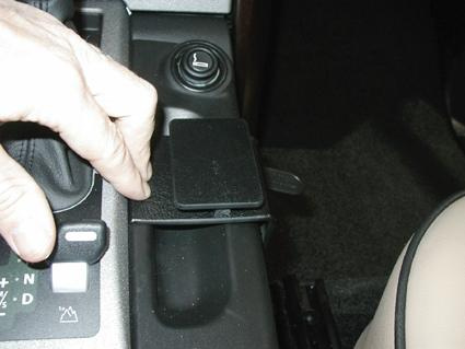 En hand som sträcker sig efter en konsol i en bil.