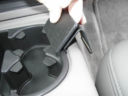 En hand håller i ett blackt plastlock för en konsol.