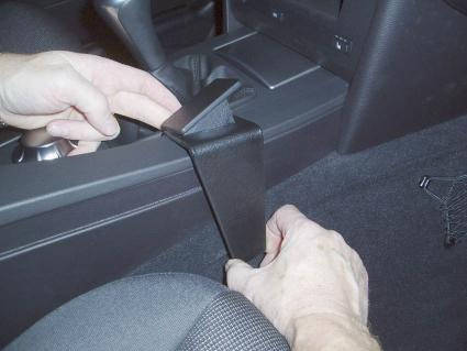 En hand som monterar en konsolkomponent i en BMW E60/E61.