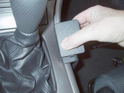 En hand som trycker på en konsolknapp i en bil.