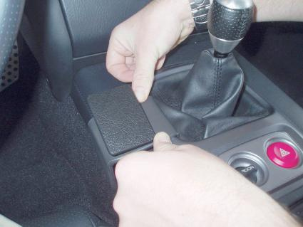 Två händer installerar en monteringsbygel i en bils mittkonsol.