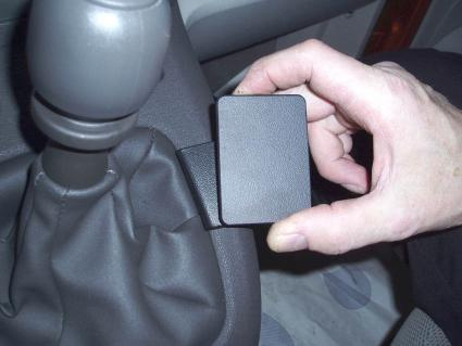 En hand håller en liten konsol vid växelspaken i en bil.