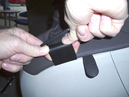 En hand visar hur man fäster en konsol på Fiat Idea.