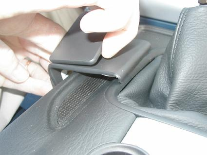 En hand som installerar en monteringsbygel på en bilkonsol.