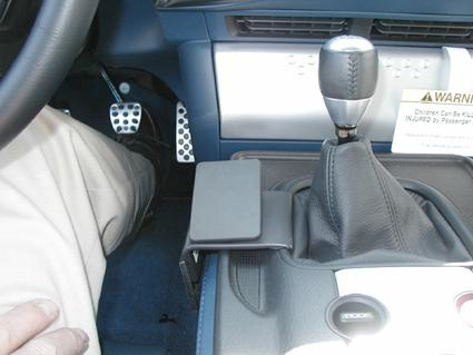 En inifrån-bild av en bils framsäte med skiftspak och pedaler.