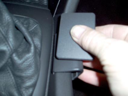 En hand som håller i en svart konsolkomponent för Saab 9-3.