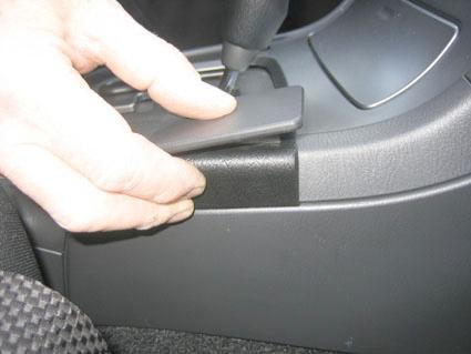 En hand justerar en del av konsolen i en Subaru Impreza 05-07.