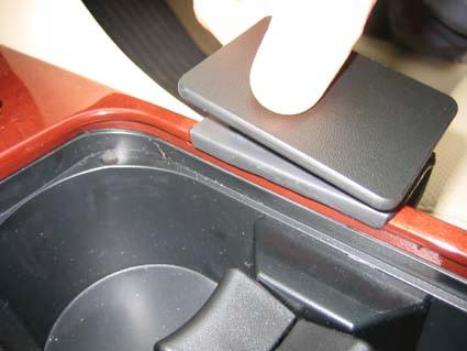 En konsol med en svart lucka och ett finger som trycker på den.