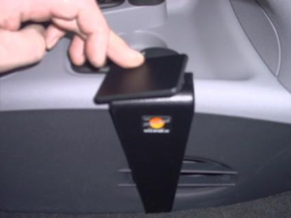 En hand trycker på en svart konsol i en bil.