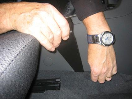 En hand som håller en monteringsbygel i en bils interiör.