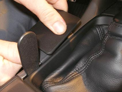 En hand som öppnar ett lock på en manuell växelspakskonsol.