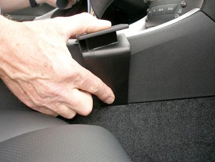 En hand trycker på en del av konsolen i en Lexus IS.