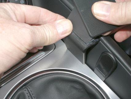 En hand tar bort en del av en konsol i en Audi TT 07-14.