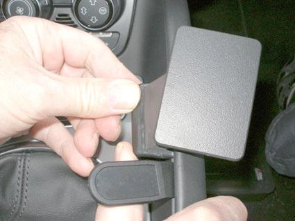 En person fäster en konsol i en Audi TT-interiör.