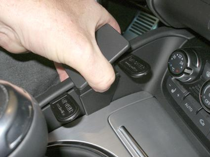 En hand placerar en konsolkomponent i en Audi TT.