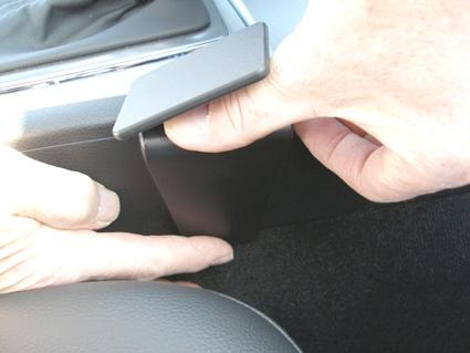 En hand justerar en svart konsol i en Mercedes Benz C-Klass.