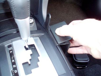 En hand som trycker på en konsol nära växelspaken i en Mitsubishi Lancer.