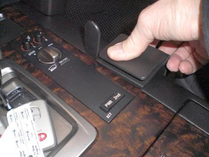 Hand som trycker på en knapp på en konsol i en Toyota LandCruiser.