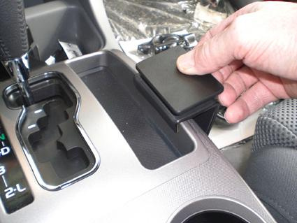 En hand placerar en svart konsol på en bils mittkonsol.