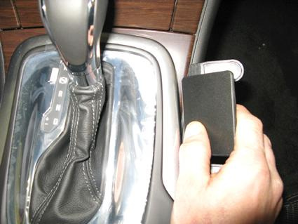 En hand håller en svart enhet nära växelspaken i en Opel Insignia.