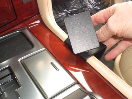 En hand placerar en svart hållare på en bilkonsol.