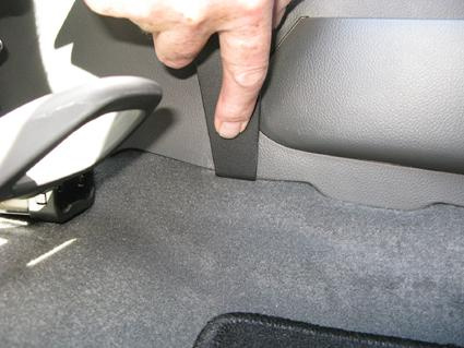 En hand pekar på en svart rem vid Chevrolet Cruze 09-14 konsolområde.