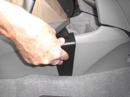 En hand håller i en svart konsoldel i en Honda Insight.