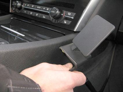 En hand trycker på en konsolplacerad knapp i en BMW F07.