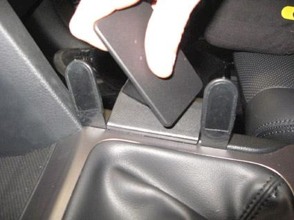 Hand som håller en svart platta över en konsol i en bil.