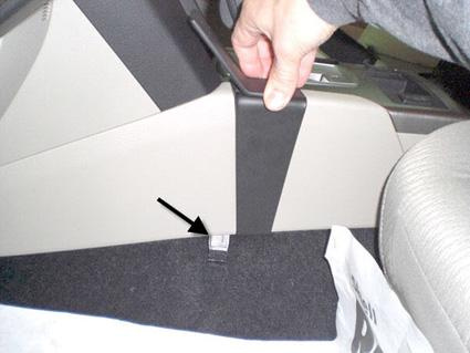 En hand som håller i en konsol vid sidan av bilen.