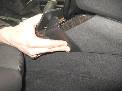 En hand håller i en konsolmonteringsdel för BMW F10, F11.