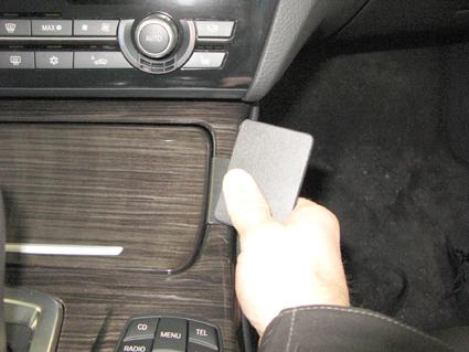 Hand som håller en svart modul vid konsolen i en BMW F10/F11.