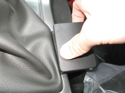 En hand trycker på en svart konsoldel i en bil.