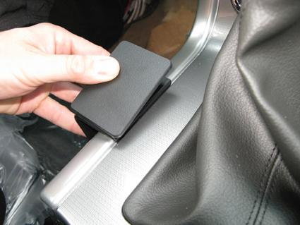 En hand som håller en svart konsolbit för Nissan Navara 11-15.