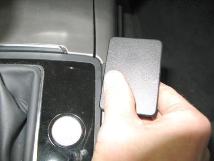 En hand håller en svart dekoration ovanför en konsol i en Audi A6.