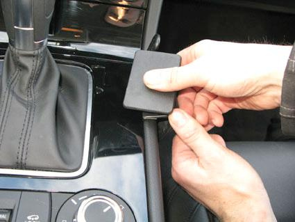 En person fäster en konsol på en bils mittkonsol.