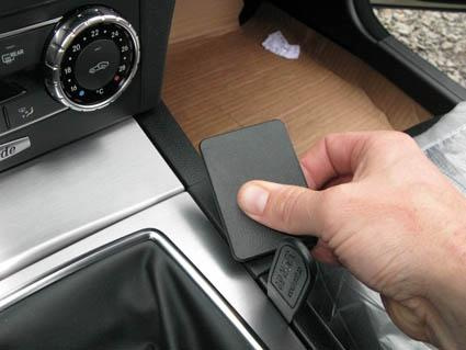 En hand håller i en svart platta vid en bilkonsol.