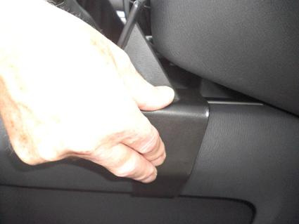 En hand greppar en del av konsolen i en Nissan Pathfinder 13-15.