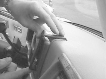 En hand fäster en monteringsbygel på en bils instrumentpanel.