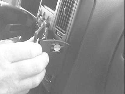 En hand som använder ett verktyg på en bils instrumentpanel.