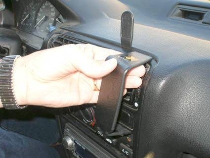 En hand installerar en vinklad monteringsbygel i en bilinteriör.