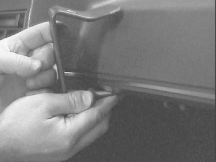 En hand håller i en vinklad del som ser ut att installeras på en Volkswagen Golf II.