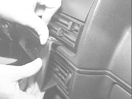 Händer som tar bort en del från instrumentpanelen i en Volkswagen Golf II.